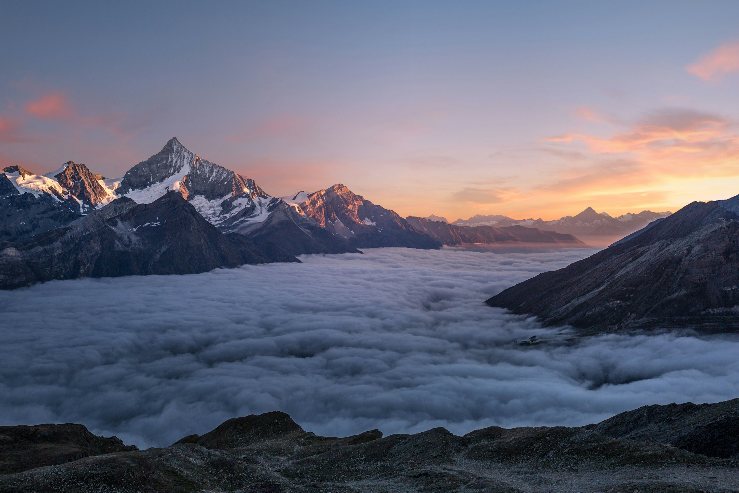 Mountain peaks above a sea of clouds at dusk